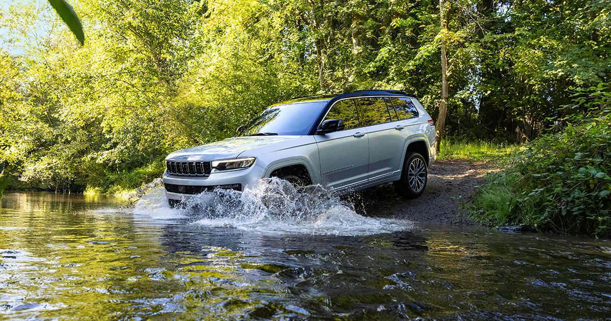 A Jeep Grand Cherokee going off-road and driving over water.