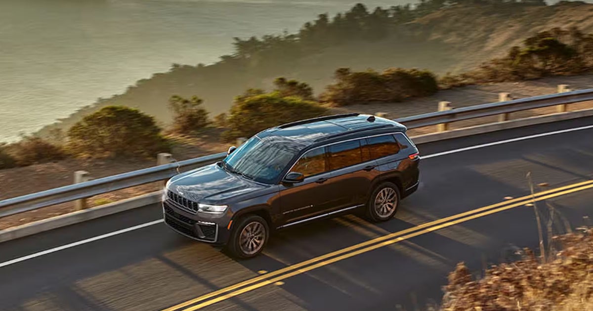 A black Jeep Grand Cherokee driving along a mountainside road.